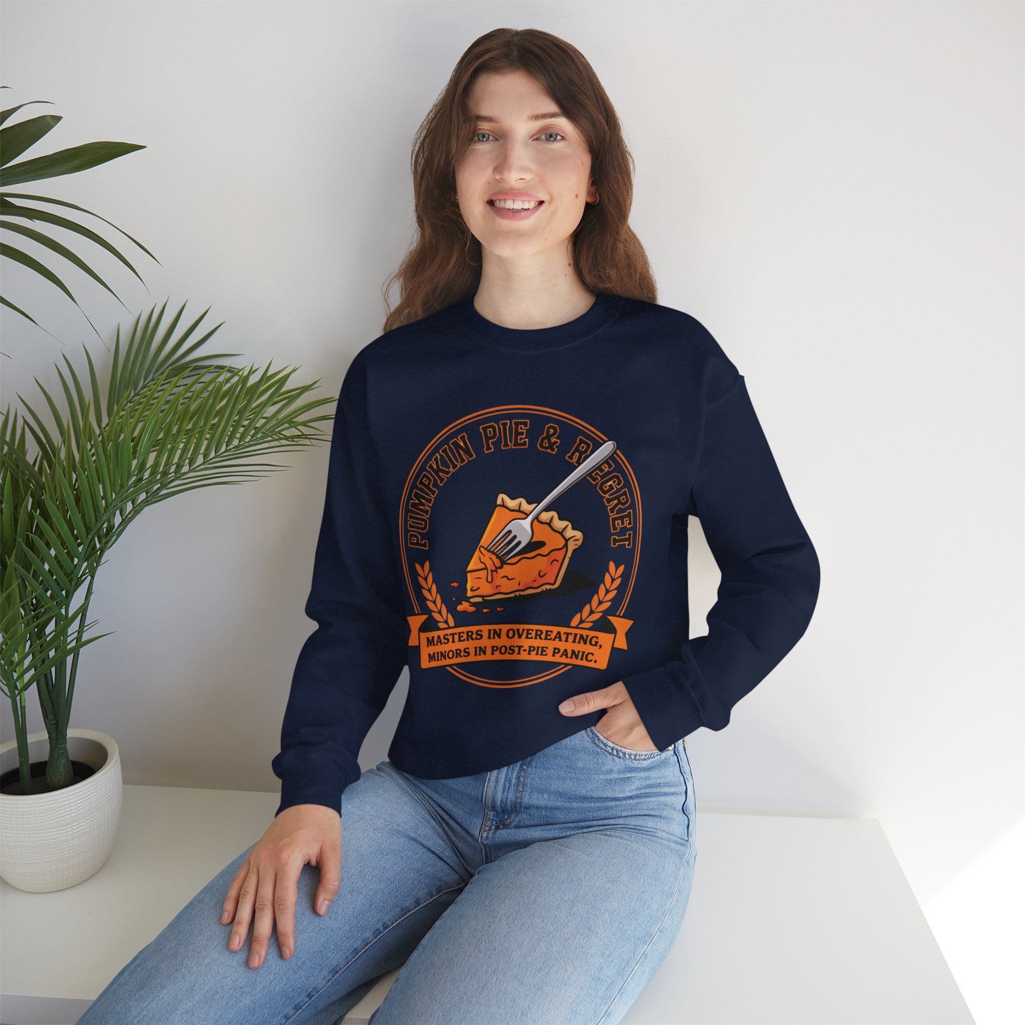 Person wearing a Navy blue sweatshirt with a graphic design, sitting on a white surface with a plant in the background.